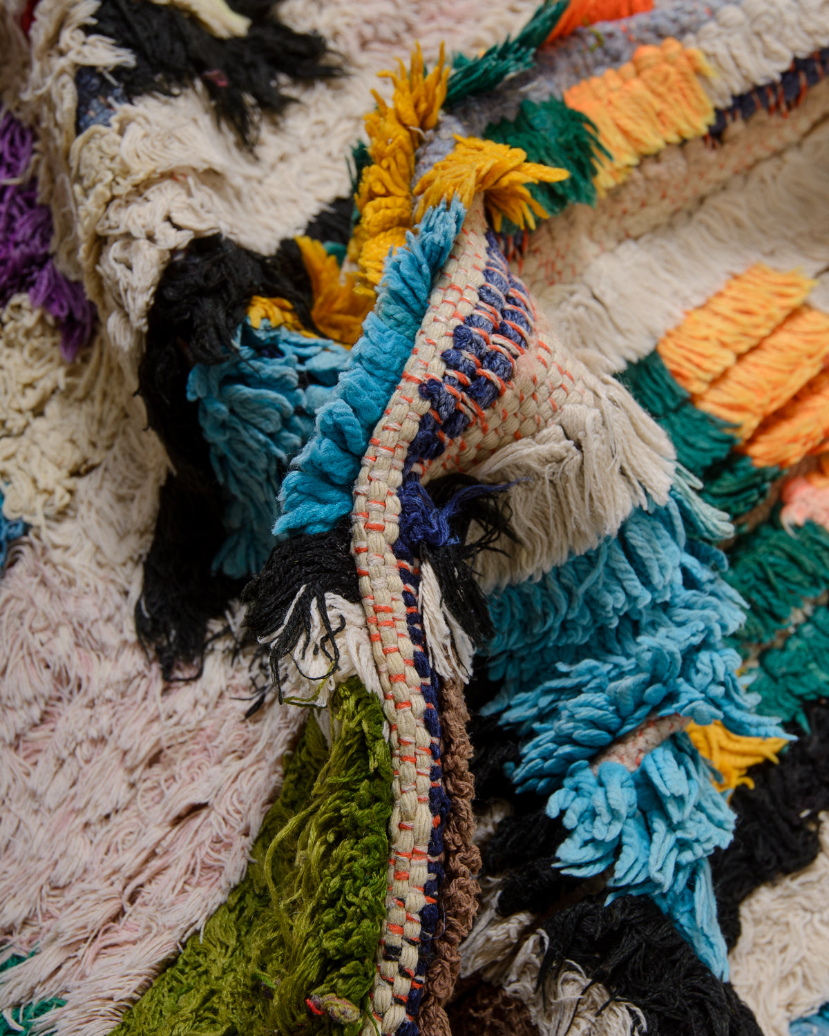 Close up texture of Berberlin vintage Boucherouite runner rug made of colourful cotton, wool and cloth.